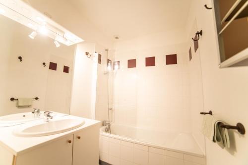 a white bathroom with a sink and a bath tub at Le Bellevue, 50m lac, piscine, parking, wifi, baignade surveillée in Aureilhan