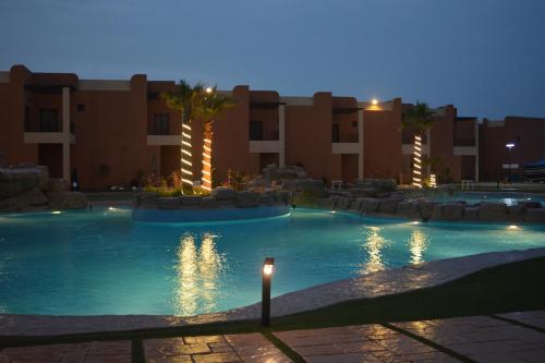 a swimming pool in a resort at night at Aquamarine Kuwait Resort(Families Only) in Al Nuwaiseeb