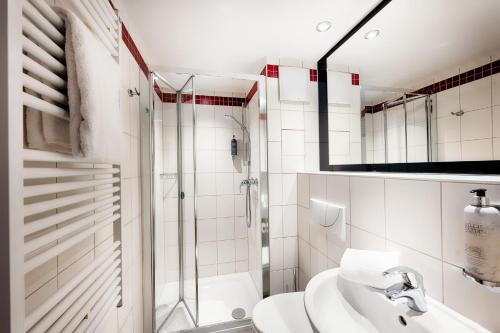 a white bathroom with a sink and a shower at Premier Inn Koeln City Centre in Cologne