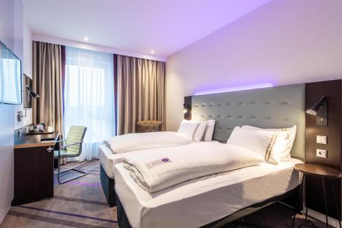 a hotel room with two beds and a desk at Premier Inn Essen City Centre in Essen