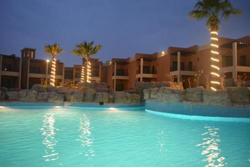 a swimming pool in front of a hotel at night at Aquamarine Kuwait Resort(Families Only) in Al Nuwaiseeb