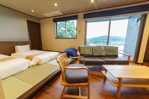 a hotel room with a bed and a couch and a table at Kisara Bettei TOKI in Toba