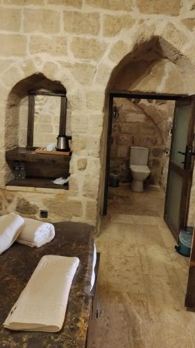 a stone bathroom with a toilet and a mirror at Kasrı Hatun Konağı in Mardin