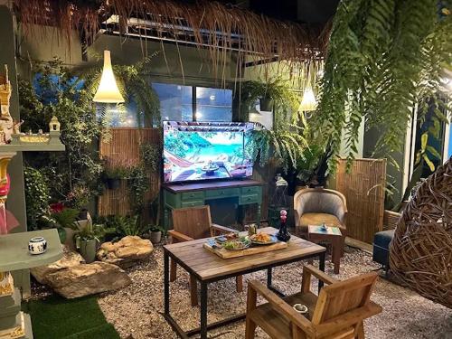 a living room with a table and a tv in it at The Oasis on 8 Cozy Homestay & Café in Bangkok