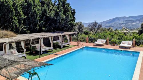a swimming pool with chairs and a gazebo at Casa EntreAzules l Vivienda Rural in Lecrin