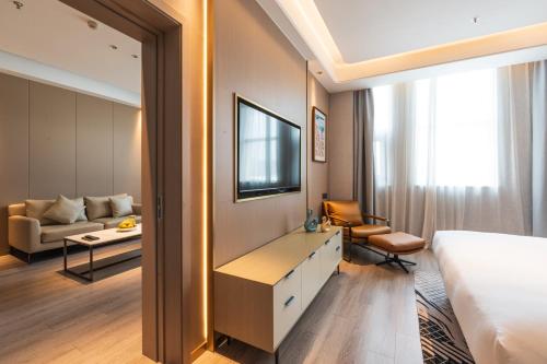 a hotel room with a bed and a desk and a couch at JOY Hotel Hangzhou in Hangzhou