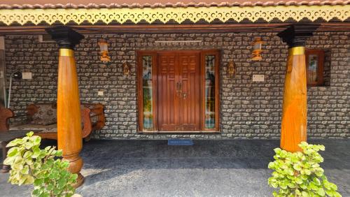 a building with two pillars and a wooden door at Lucky garden inn in Chennai