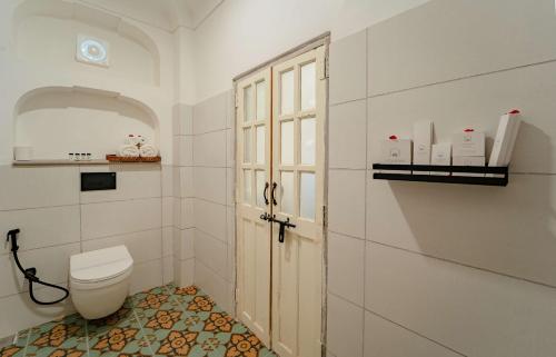 a white bathroom with a toilet and a window at Sitaram Bhawan - A 250-Year- Old Heritage Haveli, Jaipur in Jaipur