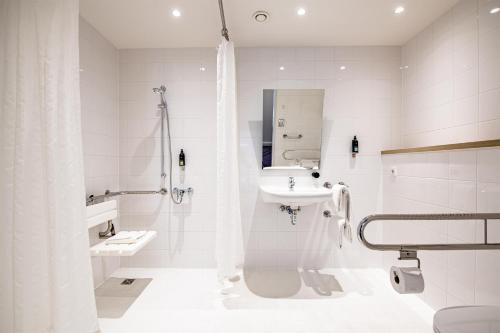 a white bathroom with a sink and a shower at Premier Inn München Messe in Haar