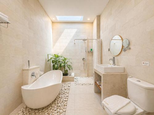 a bathroom with a tub and a sink and a mirror at D'Avera Villa Canggu in Canggu