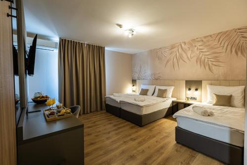 a hotel room with two beds and a desk at Hotel Klek in Ogulin