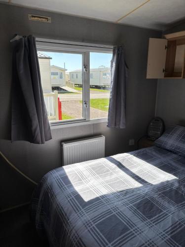 a small bedroom with a bed and a window at 6Berth Caravan-Wheelchair Accessible-Pet Friendly in Skegness
