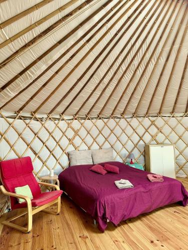 a bedroom with a bed and a chair in a yurt at Les Jardins Vert Framboise yourte et chambres d'hôtes in Beaufour
