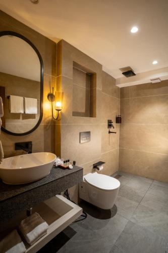 a bathroom with a sink and a toilet and a mirror at Dhulikhel Mountain Resort in Dhulikhel