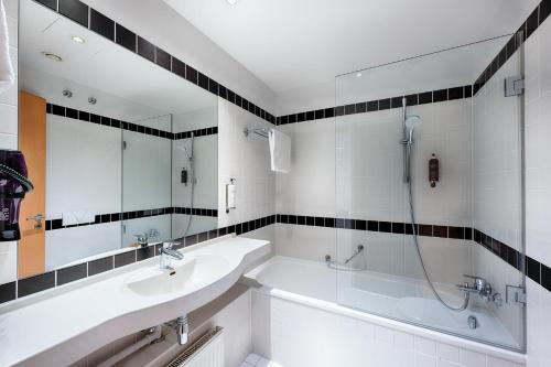 a bathroom with two sinks and a tub and a mirror at Premier Inn München City Ost in Munich