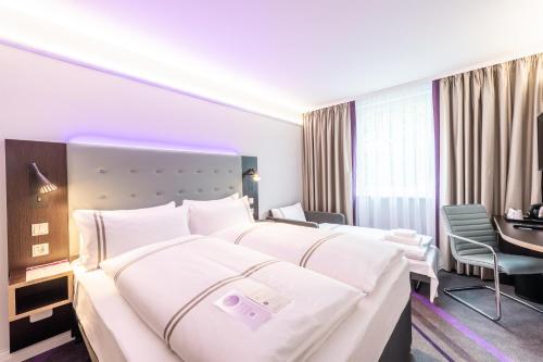 a hotel room with two beds and a desk at Premier Inn München Airport Ost in Oberding