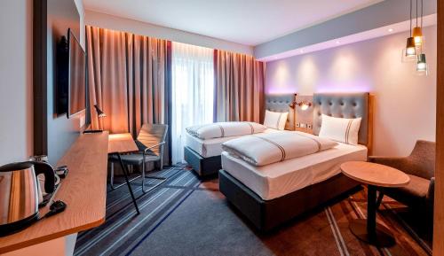 a hotel room with two beds and a desk at Premier Inn München Airport Süd in Hallbergmoos