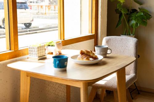 a wooden table with a plate of pastries on it at Guest House BLUE DOOR in Imabari Railway Station