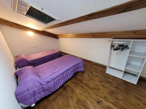 two beds in a room with purple sheets at Alojamiento Turístico Río Uces in La Zarza de Pumareda