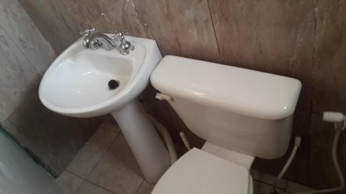 a bathroom with a white toilet and a sink at Cabañas El Paraiso in Villa Parque Siquiman