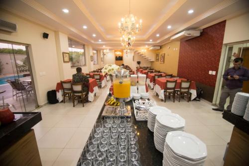 a dining room with a table with a pitcher of orange juice at Lotus Hotel - à 6 km do Santuário de Aparecida-SP in Guaratinguetá