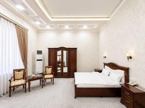 a bedroom with a bed and a table and chairs at Hayot Hotel Skazka in Qarshi