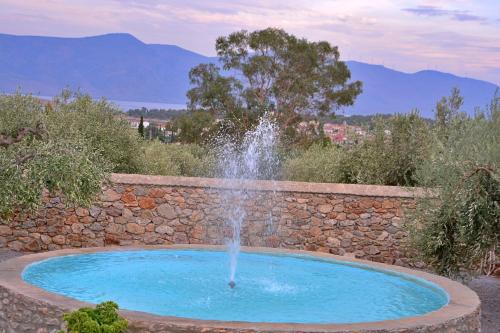 a fountain in a garden with a stone wall at Studio in the Olive Trees ΓΑΛΑΞΙΔΙ in Galaxidi