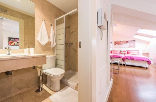 a bathroom with a sink and a toilet and a bed at Prince Santa Ana in Madrid