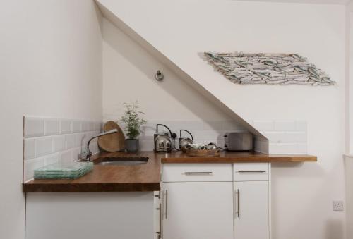 a white kitchen with a sink and a counter at Trethoway in Port Isaac