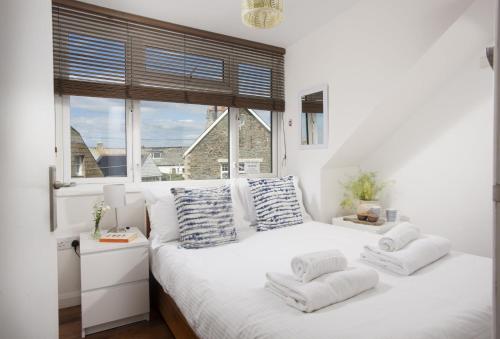 a bedroom with a white bed with pillows and a window at Trethoway in Port Isaac