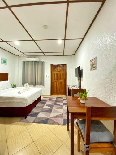 a hotel room with a bed and a desk and a table at Sunville Hotel and Restaurant in Panglao Island