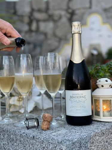 a bottle of wine sitting next to four wine glasses at Quinta de Maderne in Felgueiras