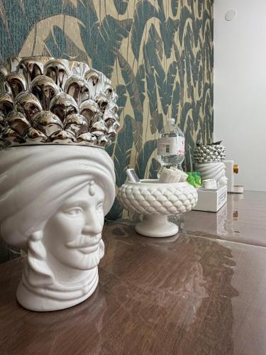 a vase with a statue of a head on a table at Elled-home in Misterbianco