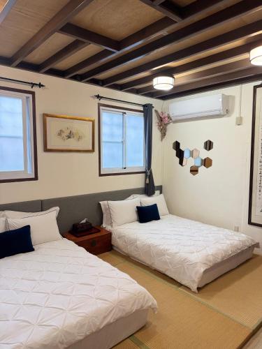 two beds in a room with two windows at 海軍官邸眷村民宿 in Nan-men