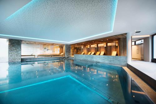 a large swimming pool with blue water in a building at Premium Activehotel Bergkönig in Neustift im Stubaital