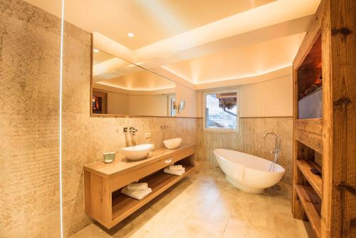 a bathroom with two sinks and a bath tub at Premium Activehotel Bergkönig in Neustift im Stubaital
