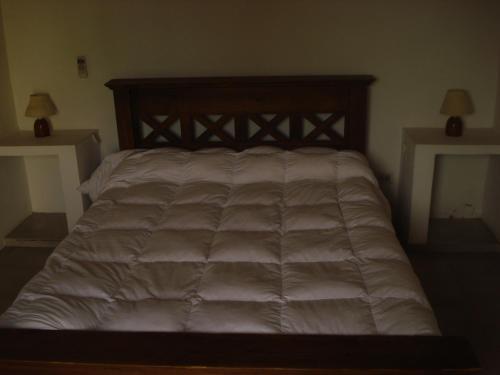 a large bed in a bedroom with two tables at Cabañas Hoja de la Tierra in Chascomús