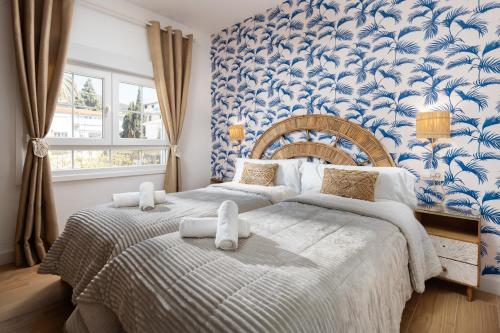 two beds in a bedroom with blue and white wallpaper at WonderStays Villa Lucía in Málaga