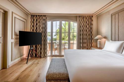 a bedroom with a bed and a flat screen tv at Grand Hotel Las Dunas, Autograph Collection in Estepona