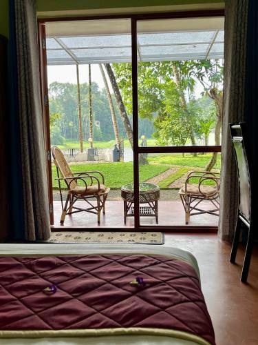 a bedroom with a large window with chairs and a patio at The River House in Cochin