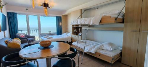 a room with bunk beds and a table and a room with a dining room at Zeezicht Studio Alisa in Blankenberge