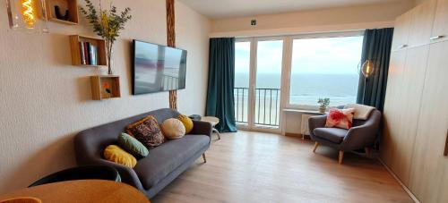 a living room with a couch and a large window at Zeezicht Studio Alisa in Blankenberge