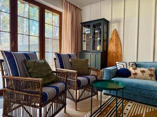 a living room with chairs and a couch and a surfboard at Sea You Beach House in Rogowo