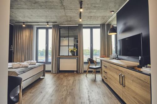 a bedroom with a bed and a desk with a television at The Bridge Suites Hotel in Krakow