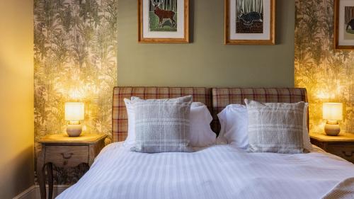 a bedroom with a bed with white sheets and pillows at The Plough in Alnwick