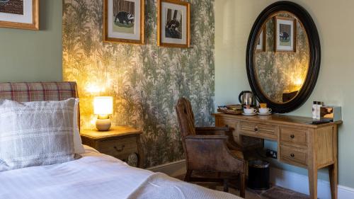 a bedroom with a bed and a desk and a mirror at The Plough in Alnwick