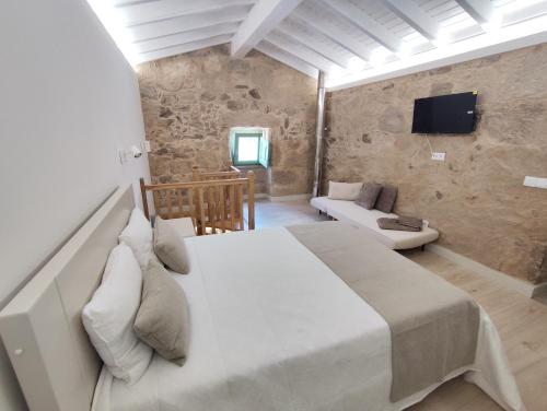 a bedroom with a large white bed and a couch at Abrigo da Serra - Soajo Mountain Lodge in Adrão