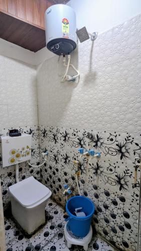 a bathroom with a toilet and a blue bucket at KSHIPRA GUEST HOUSE in Ujjain