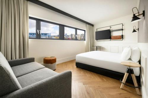 a hotel room with a bed and a couch at Moxy Paris La Villette in Paris