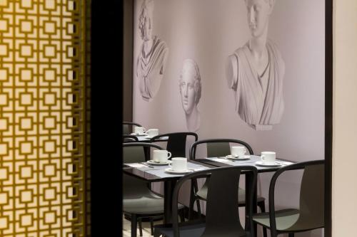 a restaurant with tables and chairs and drawings on the wall at Hotel Paris Italie in Paris